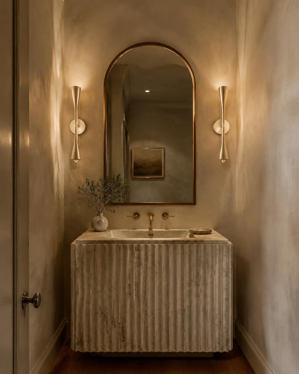 Powder room with fluted stone vanity and arched mirror